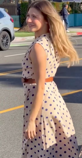Blonde woman in polka dot dress standing outdoors.