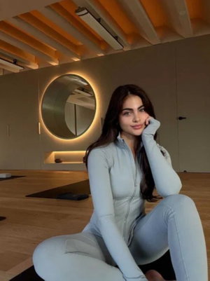 Brunette woman in light blue bodysuit sitting in modern studio.