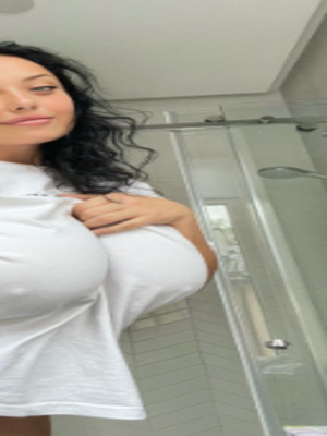 Woman with long dark hair in white t-shirt in bathroom.