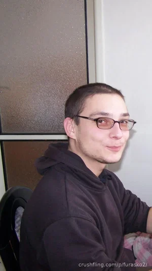 man with short hair and glasses wearing a black hoodie indoors