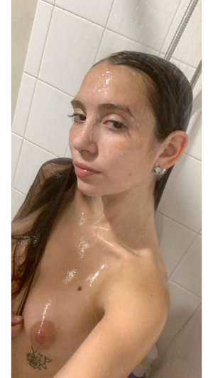 Slim woman with wet dark hair nude in shower.