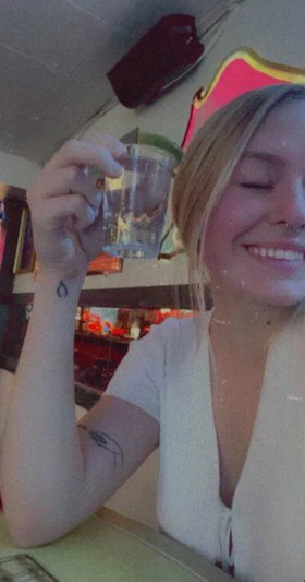 Blonde woman in white top holding glass in restaurant