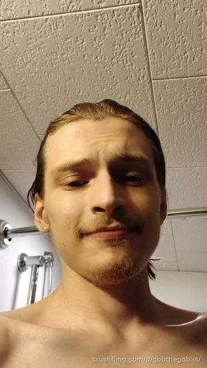 Shirtless man with wet hair and light facial hair in a bathroom.