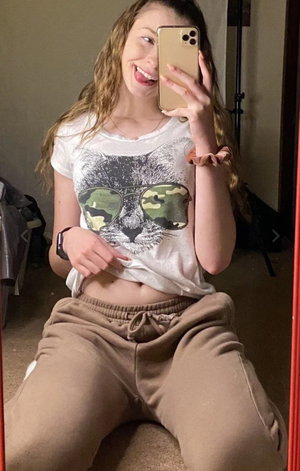 Woman with long wavy hair taking a selfie indoors in casual clothes.