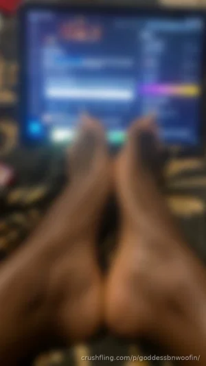 Person with bare legs and feet, sitting in front of a glowing screen, indoor setting.