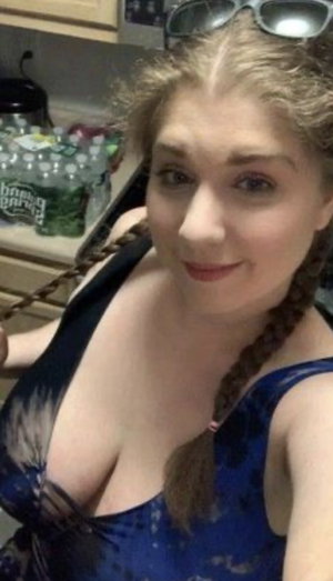 Blonde woman with braids in blue top taking kitchen selfie.