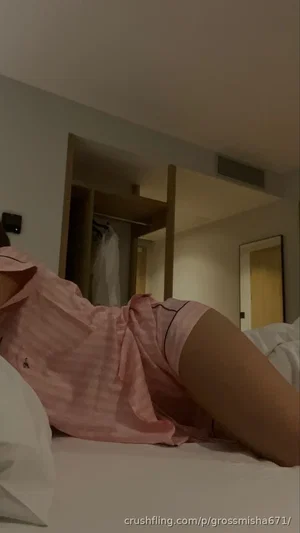 Woman in pink striped pajamas lying on bed in bedroom.
