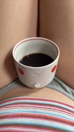 Woman in striped top holding coffee cup between thighs, wearing gray underwear.