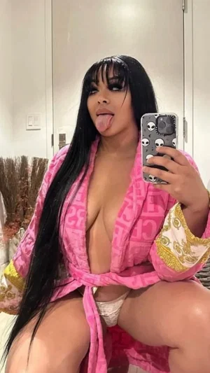 Woman with long black hair in pink robe, white underwear, posing in mirror selfie indoors.