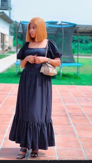 Woman in black dress with puffed sleeves, standing on brick patio outdoors near trampoline.