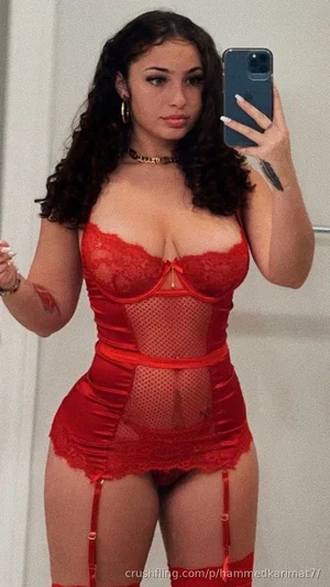 Woman in red lace lingerie taking mirror selfie, indoor setting.