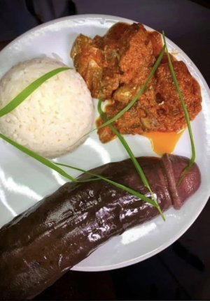 Plate with rice, curry, and a sausage-like food item garnished with green herbs.