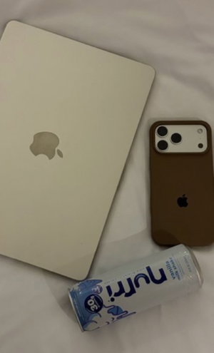 White laptop, brown phone, and Nutri-Go can on white sheets.