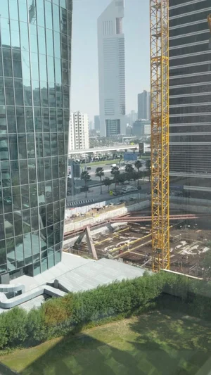 Cityscape with tall glass buildings, construction site, and yellow crane.
