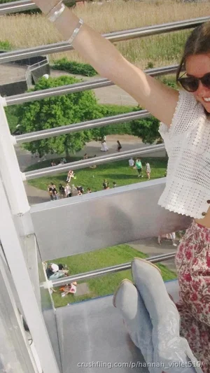 Woman in white crocheted top and floral skirt, wearing sunglasses, sitting on balcony overlooking