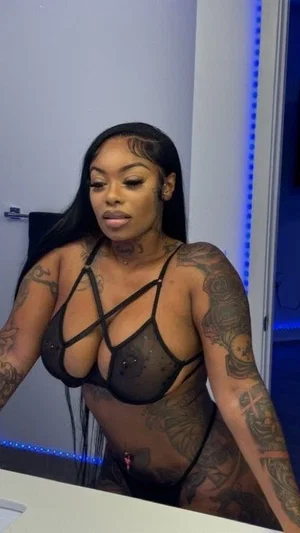 Woman with tattoos wearing black lace lingerie in a room with blue LED lights.
