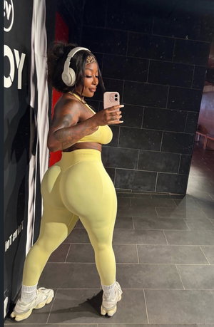 Curvy woman in yellow activewear taking a selfie indoors.