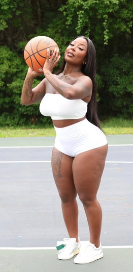 Woman in white outfit holding basketball on outdoor court.