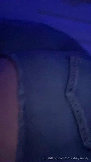 Blurry close-up of a person's torso in dim blue lighting, wearing dark clothing.