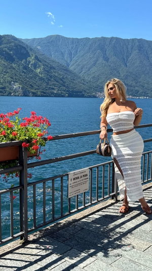 Curvy blonde in white crochet bandeau and skirt at lakeside.