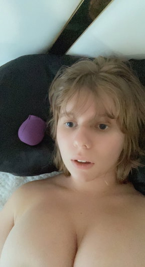 Woman with light brown hair lying on black pillow indoors.