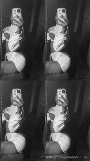 Woman in white lingerie and striped underwear taking mirror selfie in dim room.