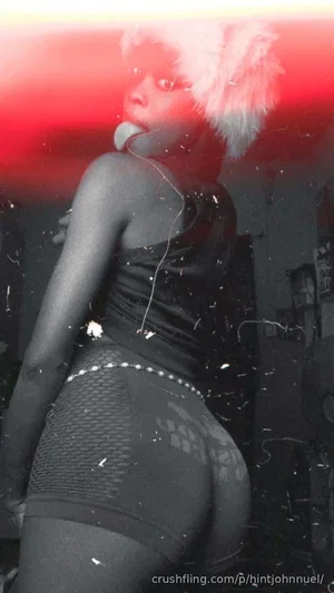 Woman in black mesh shorts and top with white fur headpiece, posing indoors.