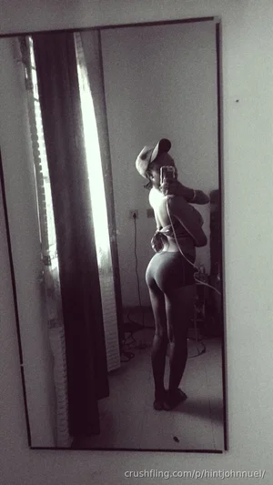 Woman in black top and shorts taking mirror selfie in indoor setting.