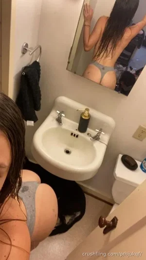 Woman with wet hair in gray underwear taking mirror selfie in bathroom.