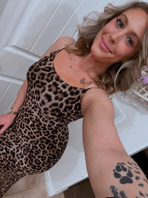 Blonde woman in leopard print dress taking selfie indoors.