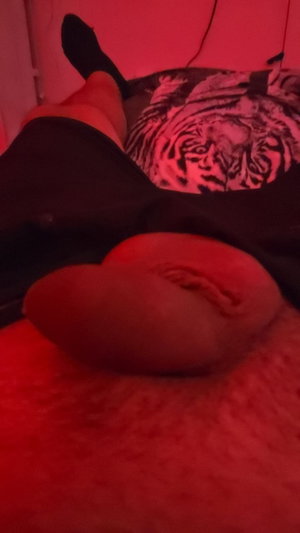 Person lying on bed with bare buttocks under red light.