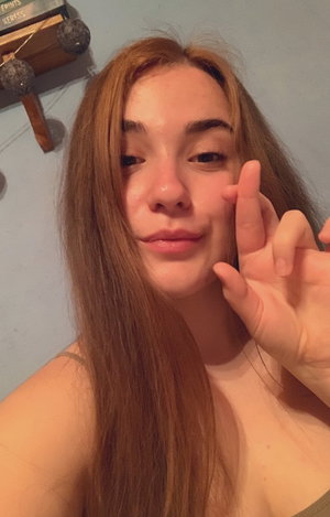 Woman with long brown hair taking a selfie indoors.