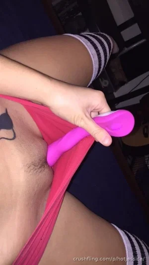 Person in pink lingerie and striped socks holding a pink toy, indoor setting.