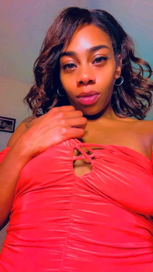 Woman in red off-shoulder top with lace-up front, indoors, looking at camera.