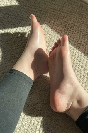 Bare feet on carpet in sunlight, dark leggings visible.
