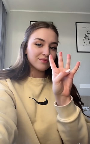 Brunette woman in beige Nike sweatshirt indoors.