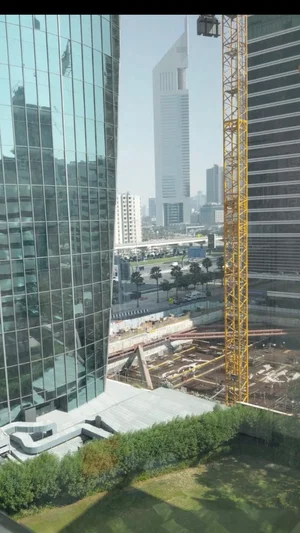 Cityscape with tall glass buildings, construction site, and yellow crane.