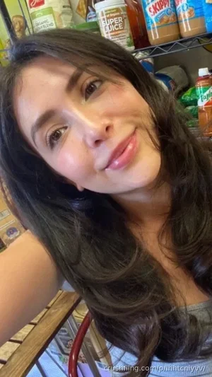 Woman with long dark hair in a tank top, smiling in a kitchen with pantry shelves behind.