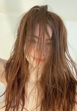 Woman with long brown hair smiling indoors.