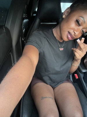 Woman in t-shirt and shorts taking selfie in car.