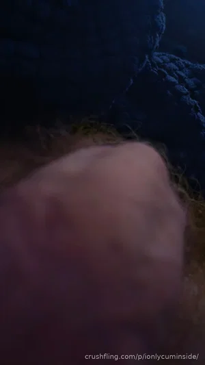 Close-up of a person's body part with curly hair, partially covered by dark fabric.