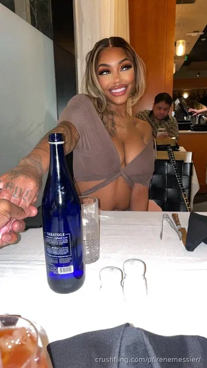 Woman with tattoos in a brown crop top at a restaurant table with drinks.