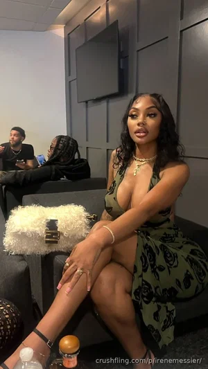 Woman in green floral dress sitting on couch, legs crossed, holding hand on knee, indoor setting.