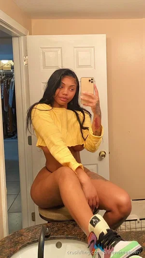 Woman in yellow crop top and black underwear, sitting on bathroom counter, mirror selfie.