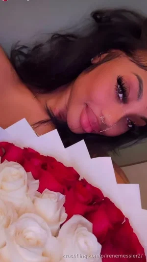 Woman with dark hair holding red and white roses, wearing minimal jewelry, indoors.