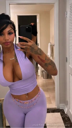 Woman in purple crop top and leggings takes mirror selfie in hallway.