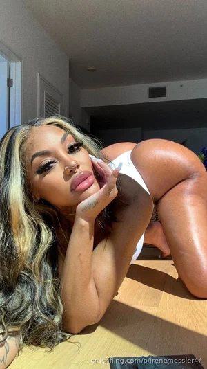 Woman with long wavy hair in white underwear posing on wooden floor indoors.