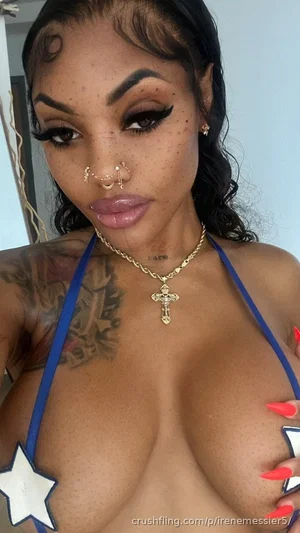 Woman with tattoos, blue halter top, star cutouts, gold cross necklace, indoor setting.