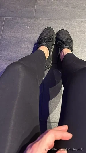 Person wearing black leggings and sneakers, standing on tiled floor, hand visible.