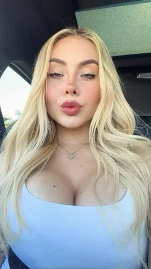 Buxom blonde in white tube top in car.